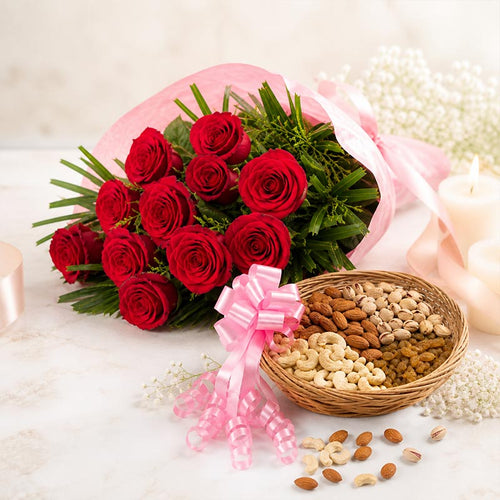 Bouquet of red roses with a pink bow and a basket of assorted nuts on a light background.