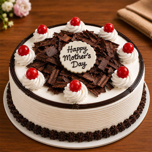 Mother's Day cake with chocolate shavings, whipped cream, and red cherries on a wooden table.