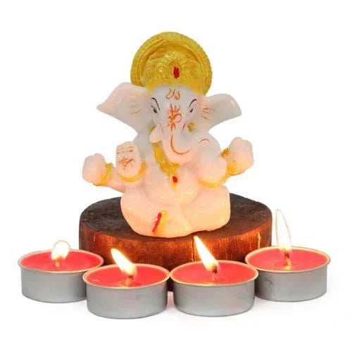 Ganesh idol with yellow crown on a wooden base, surrounded by four lit tealight candles