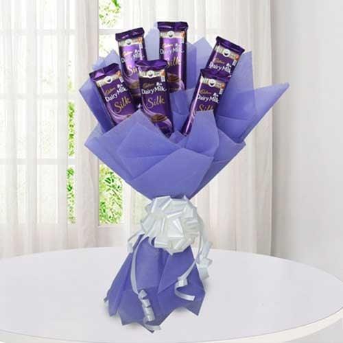 Chocolate bouquet with purple wrapping and white ribbon, arranged with Dairy Milk Silk bars.