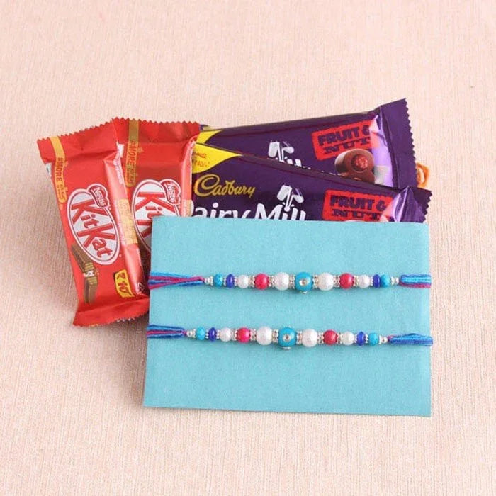 Three chocolate bars and two rakhi on a light blue card with a beige background
