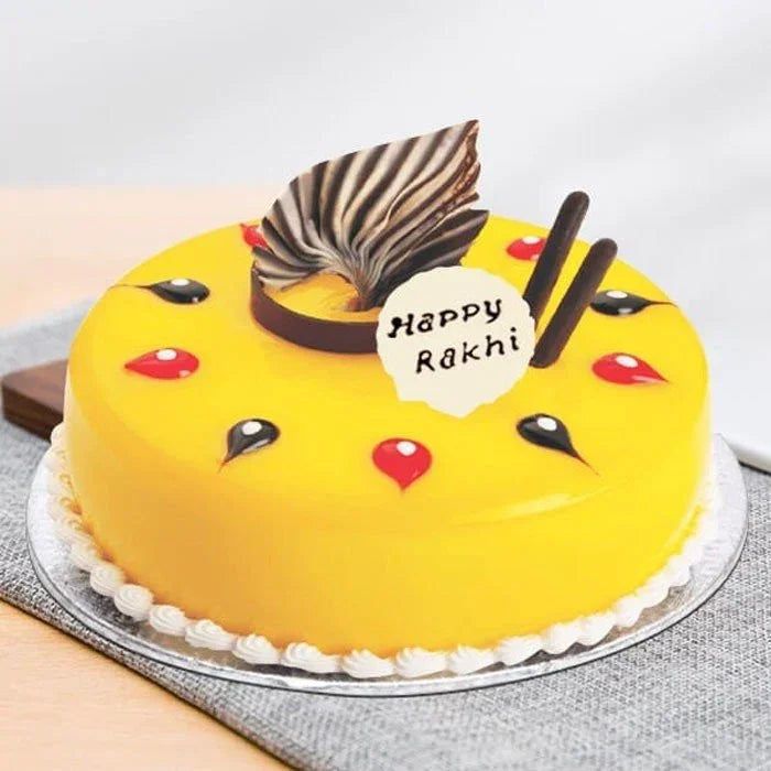 Yellow cake with decorative elements and 'Happy Rakhi' message on a white background