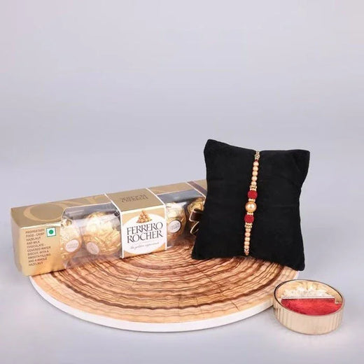 Ferrero Rocher chocolate box with a black pillow and small bowl on a wooden tray.