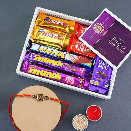 Assorted chocolate bars in a box with a Rakhi and traditional Indian powder on a gray background