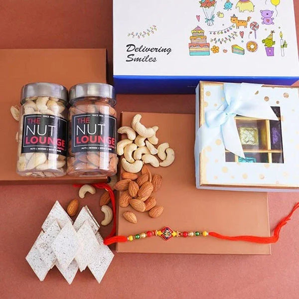 Gourmet gift set with 'The Nut Lounge' jars, nuts, cookies, and a Rakhi on a brown background.