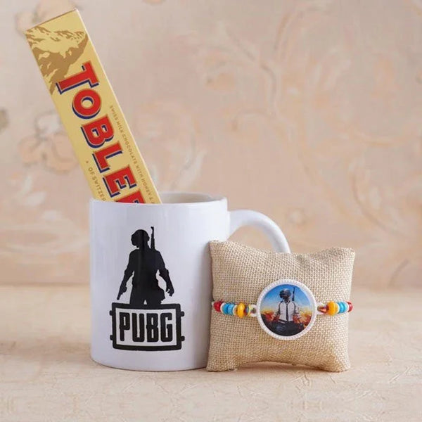 White mug with PUBG design, Toblerone chocolate bar, and small pillow with round item on a beige background