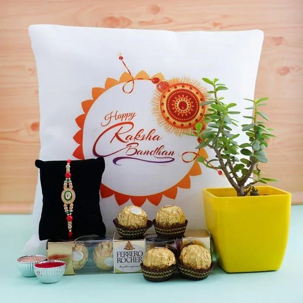Decorative pillow with 'Happy Raksha Bandhan' text, Ferrero Rocher chocolates, a plant, and a rakhi on a light blue surface.