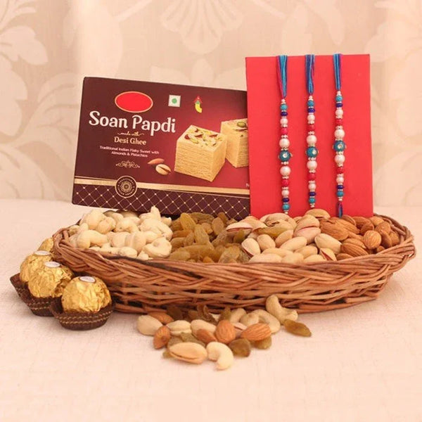 Basket of snacks with Soan Papdi box, dry fruits, and two Rakhi on a light background