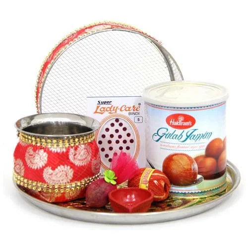 Karwa Chauth puja thali set with decorated pot, sieve, bindi, diya, and Gulab Jamun tin