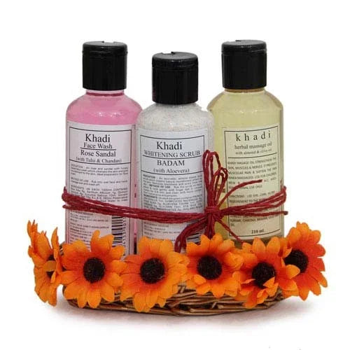 Gift basket with Khadi face wash, scrub, and massage oil in a woven tray with orange flowers