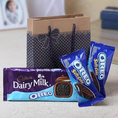 Oreo Soft Cake and Cadbury Dairy Milk Oreo packaging with a brown gift bag on a light surface.