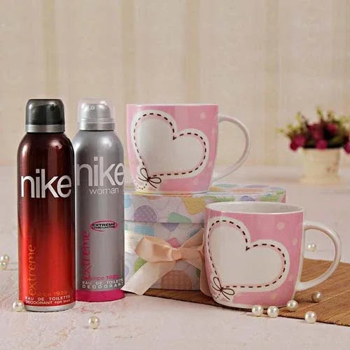 Gift set with two heart-pattern pink mugs and two Nike deodorant sprays, on a gift box