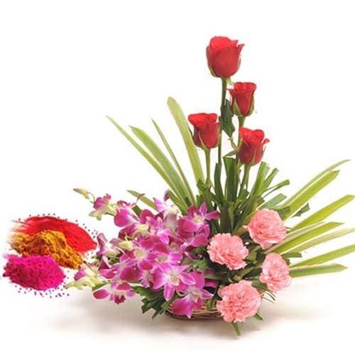 Flower arrangement with red roses, pink carnations, purple orchids, and colorful Holi powders.