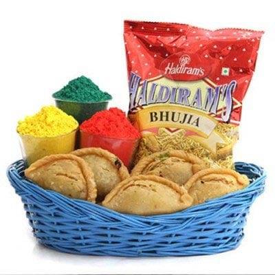 Gift basket with gujiya sweets, three colorful powders, and Haldiram's Bhujia snack pack