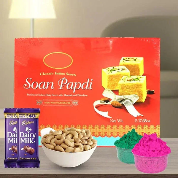 Box of Soan Papdi with Cadbury Dairy Milk chocolate, cashews, and colored powders on a table.