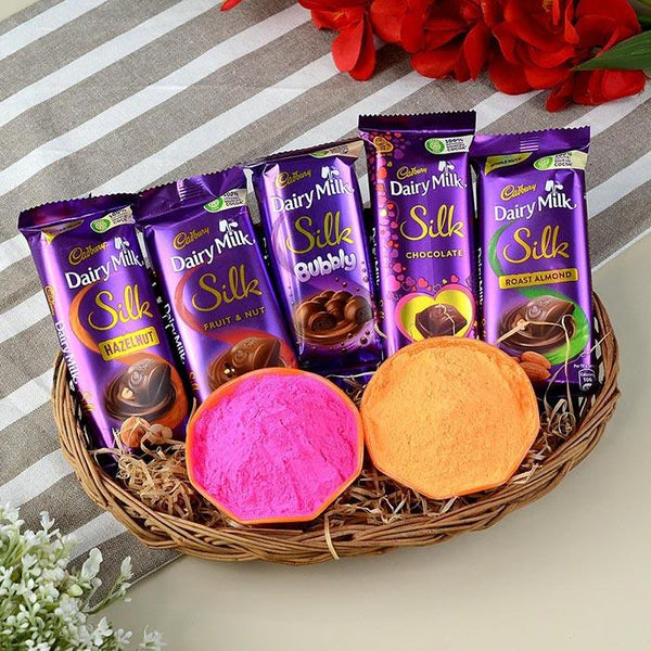 Basket of Cadbury Dairy Milk Silk chocolate bars with two colorful cookies on a striped background.