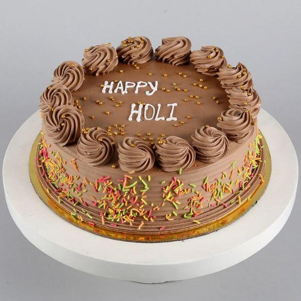 Chocolate cake with 'Happy Holi' text on a gray background