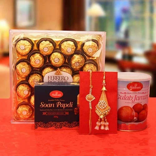 Ferrero Rocher chocolates, Soan Papdi, Gulab Jamun, and earrings on a red surface.