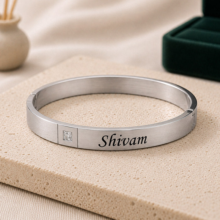 Silver bracelet with 'Shivam' engraving on a beige surface