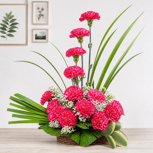 Bouquet of pink flowers with green leaves in a woven basket on a wooden surface.