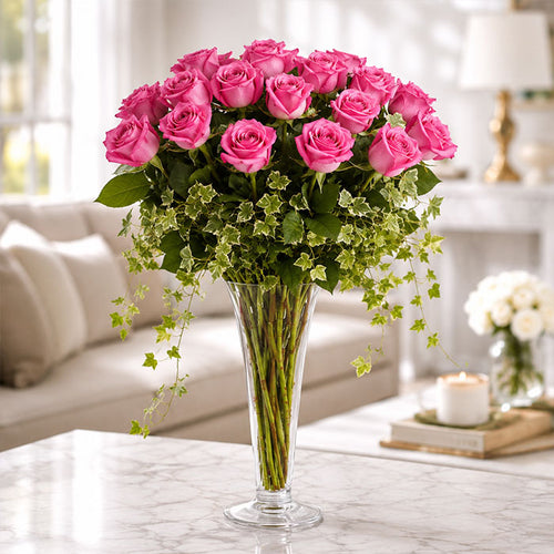 Bouquet of pink roses in a clear vase on a marble surface with a blurred background