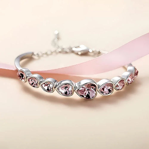 Silver bracelet with pink heart-shaped crystals on a light pink background