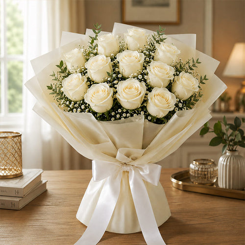 Bouquet of white roses wrapped with a white ribbon on a wooden table.