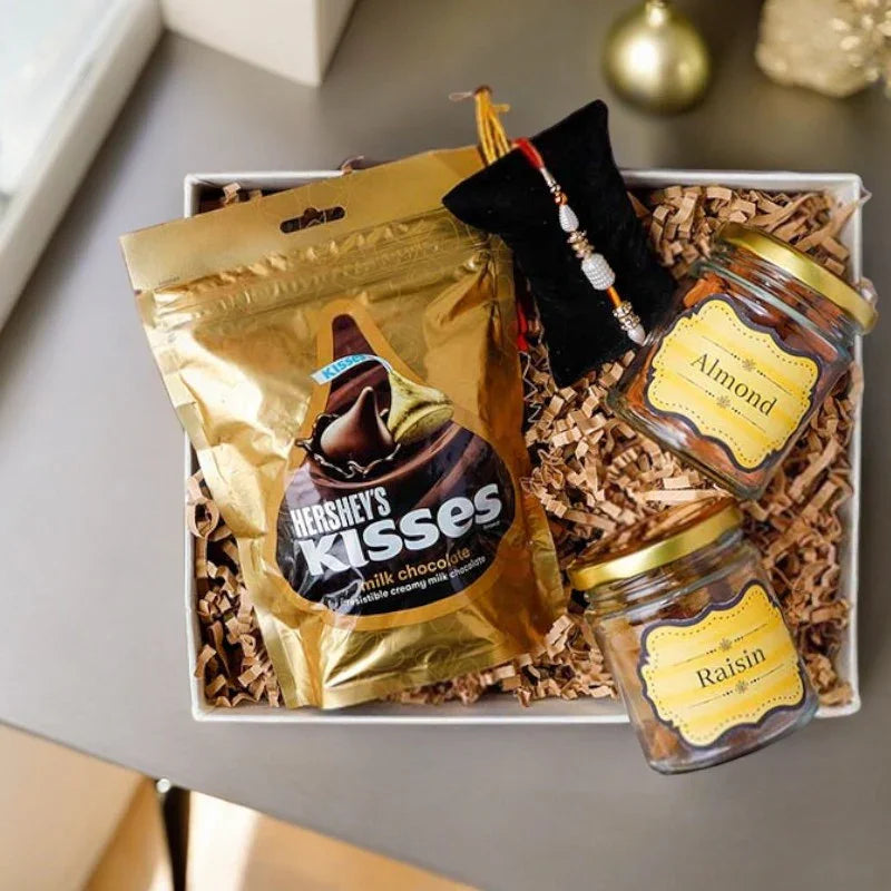Gift basket with Hershey's Kisses, almonds, and raisins on a gray surface.