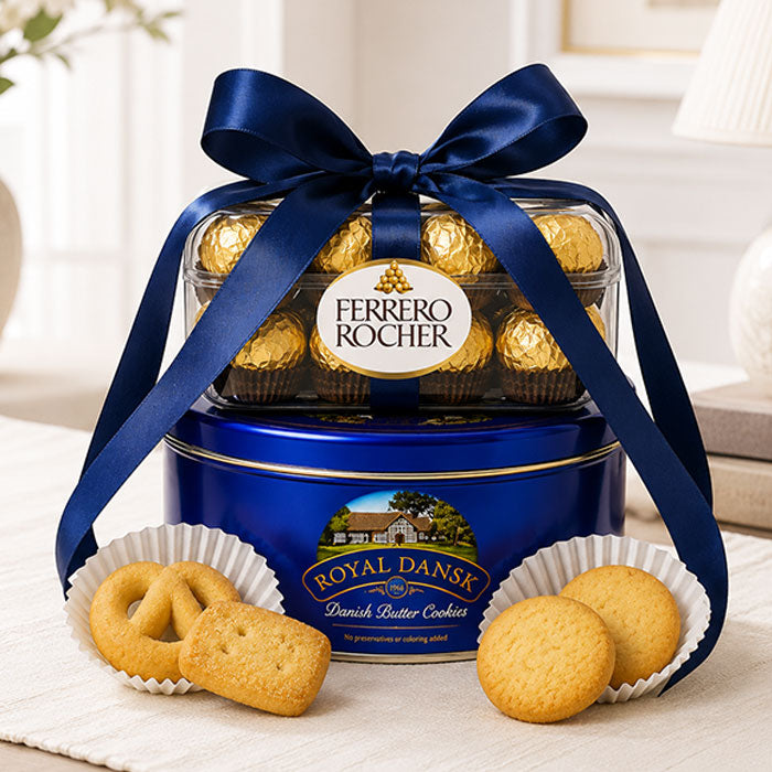 Ferrero Rocher chocolate tin with a blue ribbon and Royal Dansk cookies on a light surface.