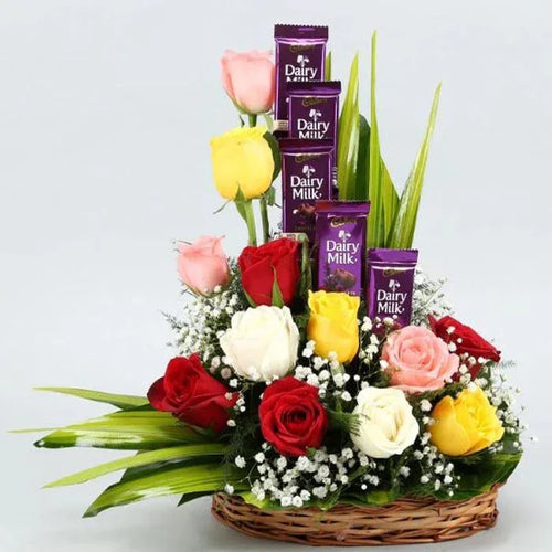 Bouquet of colorful roses with Dairy Milk chocolate bars in a basket on a light gray background