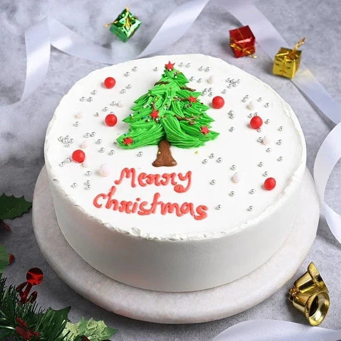Christmas-themed cake with a tree and 'Merry Christmas' text on a marble surface.