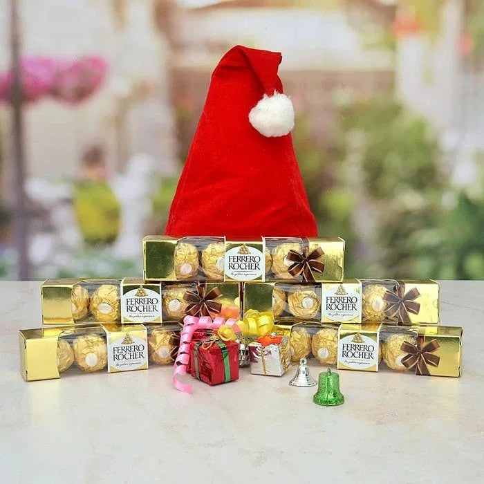 Ferrero Rocher chocolates with a Santa hat on a light surface.