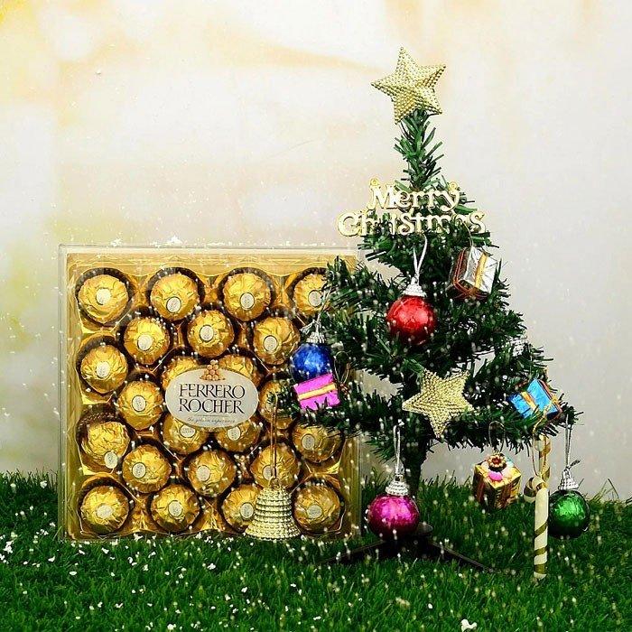 Ferrero Rocher chocolate set with a Christmas tree and decorations on a grassy surface.