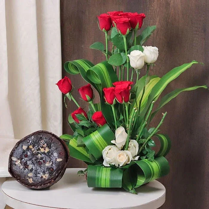 Bouquet of red and white roses with green leaves on a white surface, with a brownie in the foreground.