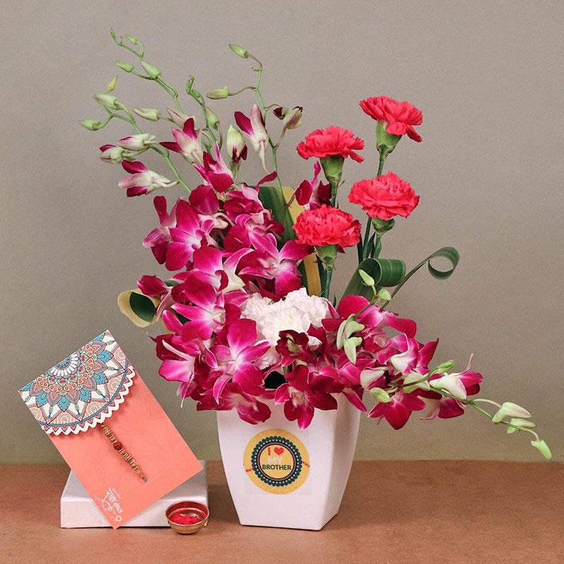 Bouquet of flowers in a white container with a card on a brown surface.