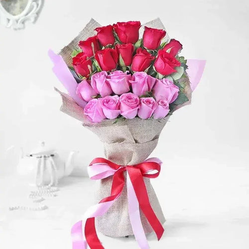 Bouquet of red and pink roses wrapped in brown paper with a pink ribbon on a white background