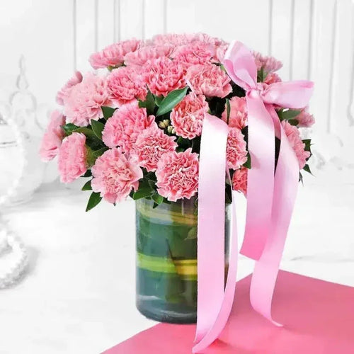 Bouquet of pink flowers in a vase with a pink ribbon on a white background
