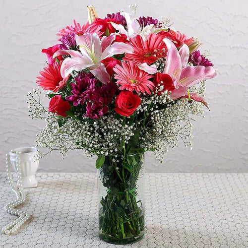 Bouquet of colorful flowers in a clear vase on a textured surface with a light background