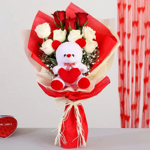 Bouquet of red and white roses with a teddy bear holding a heart, against a light gray background.
