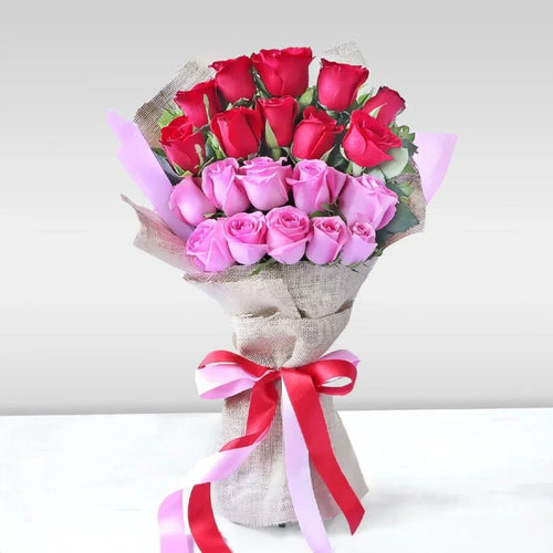 Bouquet of red and pink roses with a decorative ribbon on a white background