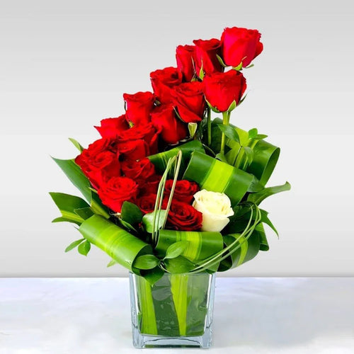 Bouquet of red roses with a white rose in a clear vase on a white background