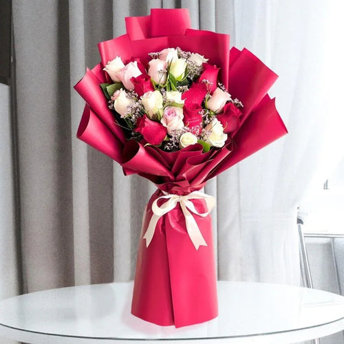 Bouquet of flowers wrapped in red paper on a glass table with a neutral background
