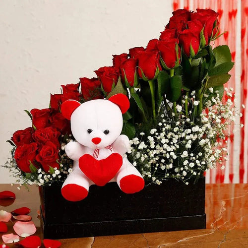 Bouquet of red roses with a white teddy bear holding a red heart on a light background.