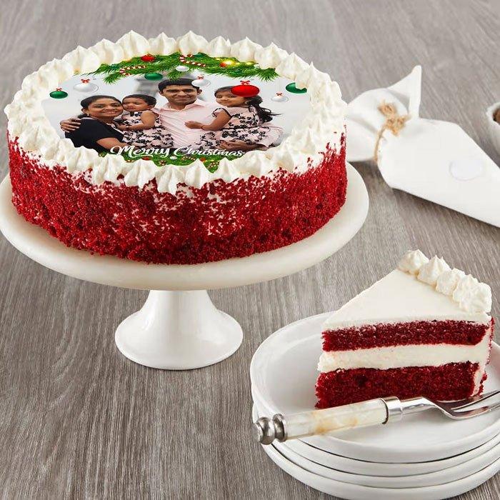 Red velvet cake with a photo of a family on top, served on a white plate with a slice taken out.