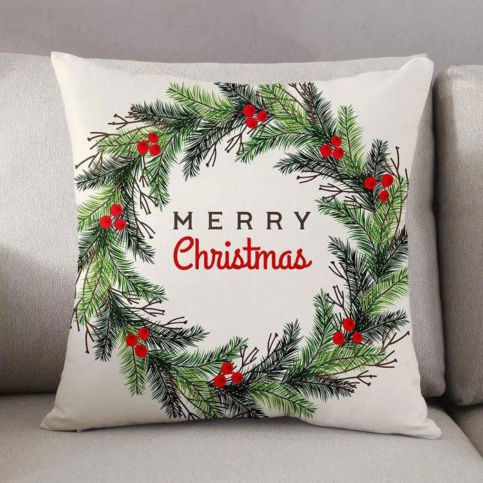 Decorative pillow with Christmas wreath design and 'Merry Christmas' text on a gray couch.