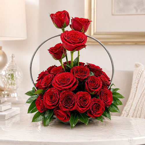 Bouquet of red roses in a decorative metal hoop on a marble surface.