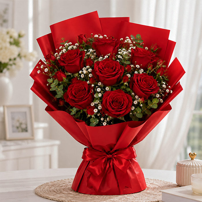 Bouquet of red roses wrapped in red paper with a bow, set against a blurred indoor background.