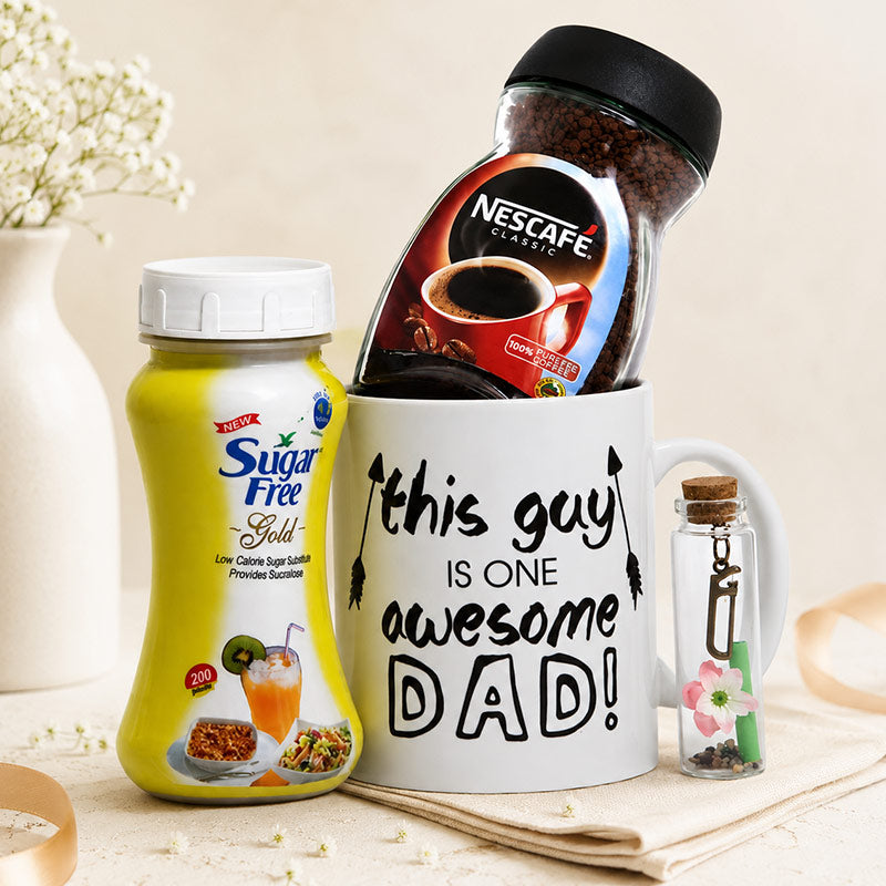 Coffee set with 'This guy is one awesome dad' mug, Nescafe jar, Sugar Free Gold container, and small bottle with keychain.