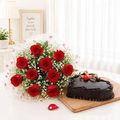 Bouquet of red roses and a chocolate cake on a wooden board with a white curtain background.
