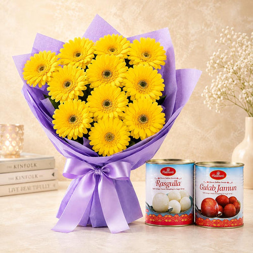 Bouquet of yellow flowers wrapped in purple paper with two cans of Haldiram's Rasgulla and Gulab Jamun on a beige background.